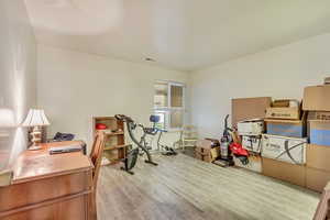 Home office with light wood-type flooring and visible vents