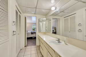Ensuite bathroom featuring tile patterned flooring, a closet, vanity, and ensuite bath