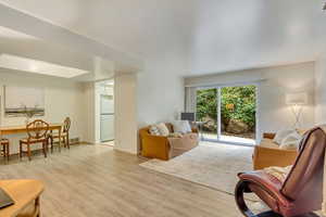 Living area with light wood-style flooring, visible vents, and baseboards