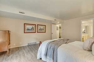 Bedroom with light wood-style floors, visible vents, and baseboards