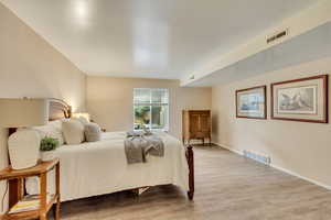 Bedroom with baseboards, visible vents, and wood finished floors