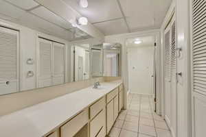 Bathroom featuring a paneled ceiling, a closet, vanity, and tile patterned floors