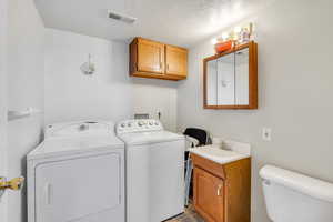 Laundry room featuring laundry area, visible vents, washer and clothes dryer, a textured ceiling, and a sink