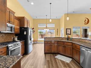 Kitchen featuring a wealth of natural light, brown cabinets, appliances with stainless steel finishes, light wood-style floors, and a sink