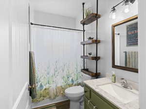 Bathroom featuring shower / tub combo, toilet, wood finished floors, and vanity