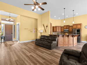 Living area featuring recessed lighting, ceiling fan with notable chandelier, baseboards, and light wood finished floors