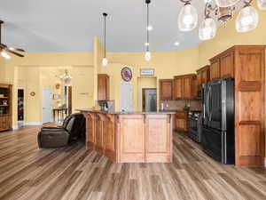 Kitchen featuring ceiling fan with notable chandelier, open floor plan, stainless steel appliances, dark stone counters, and a breakfast bar area