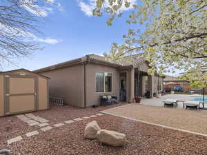 Back of house with fence, stucco siding, a storage shed, a tiled roof, and a patio area