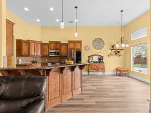 Kitchen with dark stone countertops, visible vents, appliances with stainless steel finishes, a kitchen bar, and backsplash