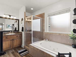 Full bathroom featuring wood finished floors, a shower stall, vanity, and a whirlpool tub