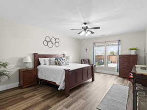 Bedroom featuring ceiling fan, baseboards, a textured ceiling, and light wood-style flooring