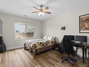 Bedroom featuring visible vents, ceiling fan, baseboards, and wood finished floors