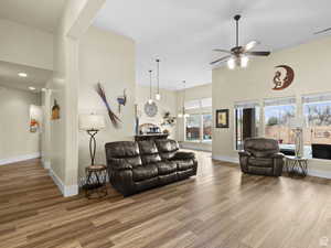 Living room featuring wood finished floors, a ceiling fan, a towering ceiling, and recessed lighting