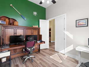 Home office with lofted ceiling, baseboards, light wood-style floors, and a ceiling fan