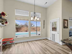 Dining room with wood finished floors, a chandelier, healthy amount of natural light, and a high ceiling