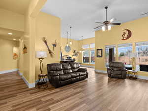 Living room featuring a ceiling fan, wood finished floors, visible vents, and a towering ceiling