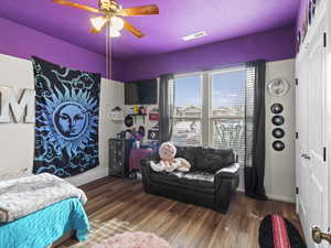 Bedroom with wood finished floors, visible vents, and a closet