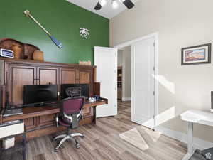 Office area featuring light wood-type flooring, ceiling fan, and a high ceiling