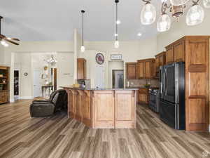 Kitchen with stainless steel appliances, a chandelier, light wood-style flooring, stone counters, and a high ceiling