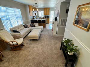 Living room featuring ornamental molding, visible vents, a textured ceiling, and carpet flooring