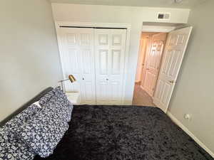 Carpeted bedroom with a closet, visible vents, a textured ceiling, and baseboards