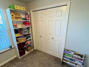 Game room with baseboards, dark colored carpet, and a textured ceiling