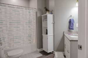 Bathroom with shower / bath combo, baseboards, vanity, and toilet