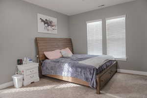 Bedroom with light colored carpet, visible vents, and baseboards