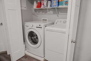 Clothes washing area featuring laundry area, dark wood-type flooring, and washing machine and clothes dryer