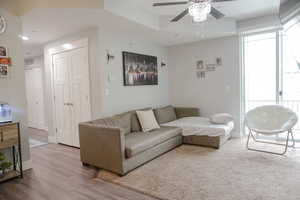 Living area with light wood-type flooring, baseboards, visible vents, and ceiling fan