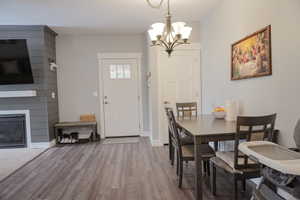 Dining space featuring baseboards, a fireplace, wood finished floors, and a notable chandelier