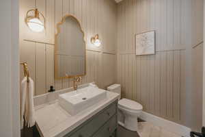 Bathroom with toilet, marble finish floor, and vanity