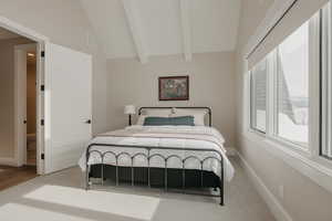 Bedroom featuring light colored carpet, visible vents, lofted ceiling with beams, and baseboards