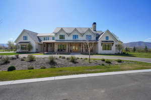 View of front facade featuring covered porch, a chimney, fence, a front lawn, and a standing seam roof