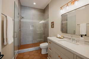 Full bathroom with toilet, tile patterned floors, vanity, a shower stall, and recessed lighting