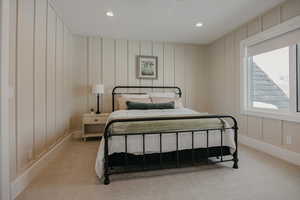 Bedroom with light carpet, recessed lighting, and a decorative wall