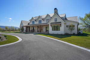 Modern farmhouse style home featuring a chimney, a standing seam roof, metal roof, a porch, and a front lawn