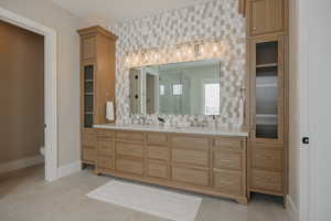 Full bathroom featuring double vanity, a shower stall, baseboards, and a sink