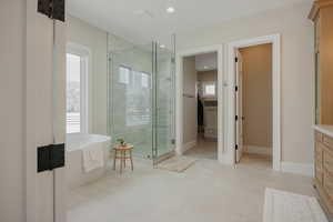 Bathroom featuring a soaking tub, a spacious closet, a shower stall, vanity, and baseboards