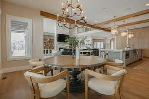 Dining space with light wood finished floors, a fireplace, and a chandelier