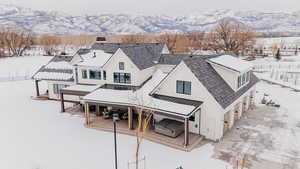 Snow covered back of property with a standing seam roof, a mountain view, and metal roof