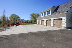 Exterior space featuring aphalt driveway, fence, a high end roof, a mountain view, and a playground