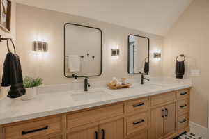 Full bath with lofted ceiling, a sink, and double vanity