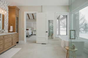 Bathroom featuring a healthy amount of sunlight, connected bathroom, a freestanding bath, and vanity