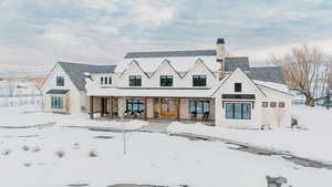 Snow covered house featuring covered porch and a chimney