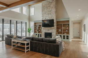 Living room featuring high vaulted ceiling, a fireplace, and light wood-style flooring