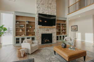 Living room featuring light wood-style floors, a fireplace, and a high ceiling