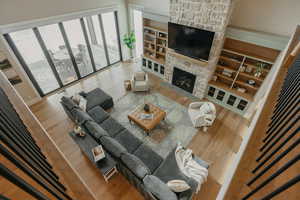 Living room featuring built in shelves, wood finished floors, and a stone fireplace