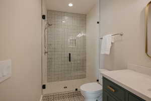 Full bathroom with toilet, a shower stall, and vanity