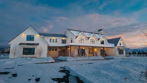 Modern farmhouse style home featuring stone siding, a chimney, and a porch